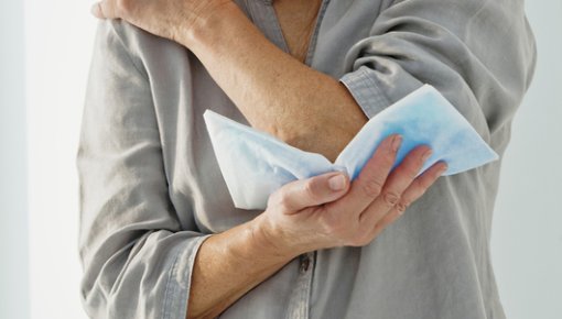 Photo of a woman holding a cold pack against her elbow