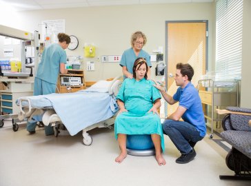 Photo of a woman in labor sitting in a hospital room 