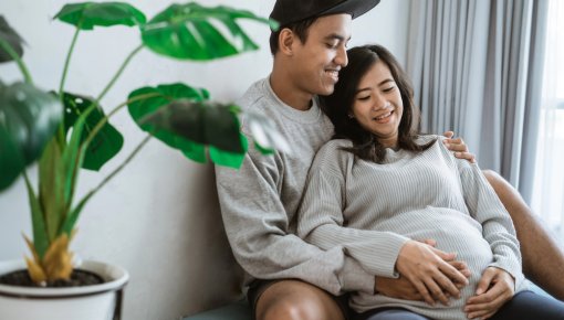 Photo of a pregnant woman and her partner, who is hugging her