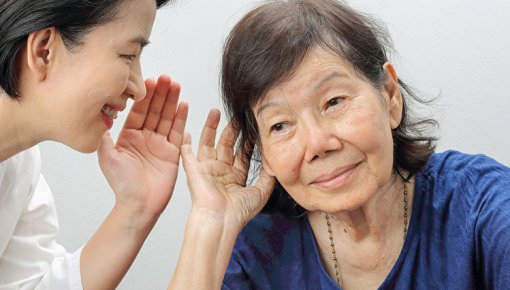 Photo of one woman talking into another woman's ear