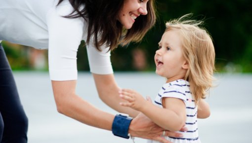 Photo of a woman with a wrist brace lifting up a child