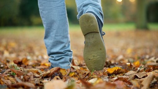 Photo of a man's feet walking through autumn leaves