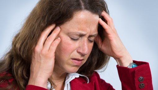 Photo of a woman frowning and holding her head