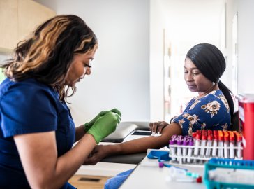 Photo of a doctor taking a sample of blood from a patient