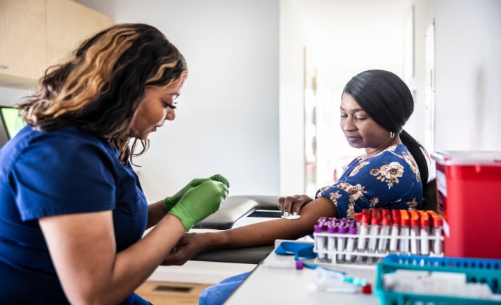 Photo of a doctor taking a sample of blood from a patient