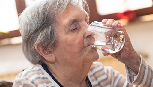 Photo of an elderly lady drinking a glass of water