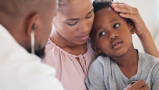 Photo of a child with a fever being examined by a doctor