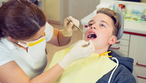 Photo of a teenager having his teeth checked by a dentist