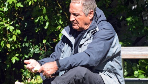 Photo of a man sitting on a bench with one shoe off